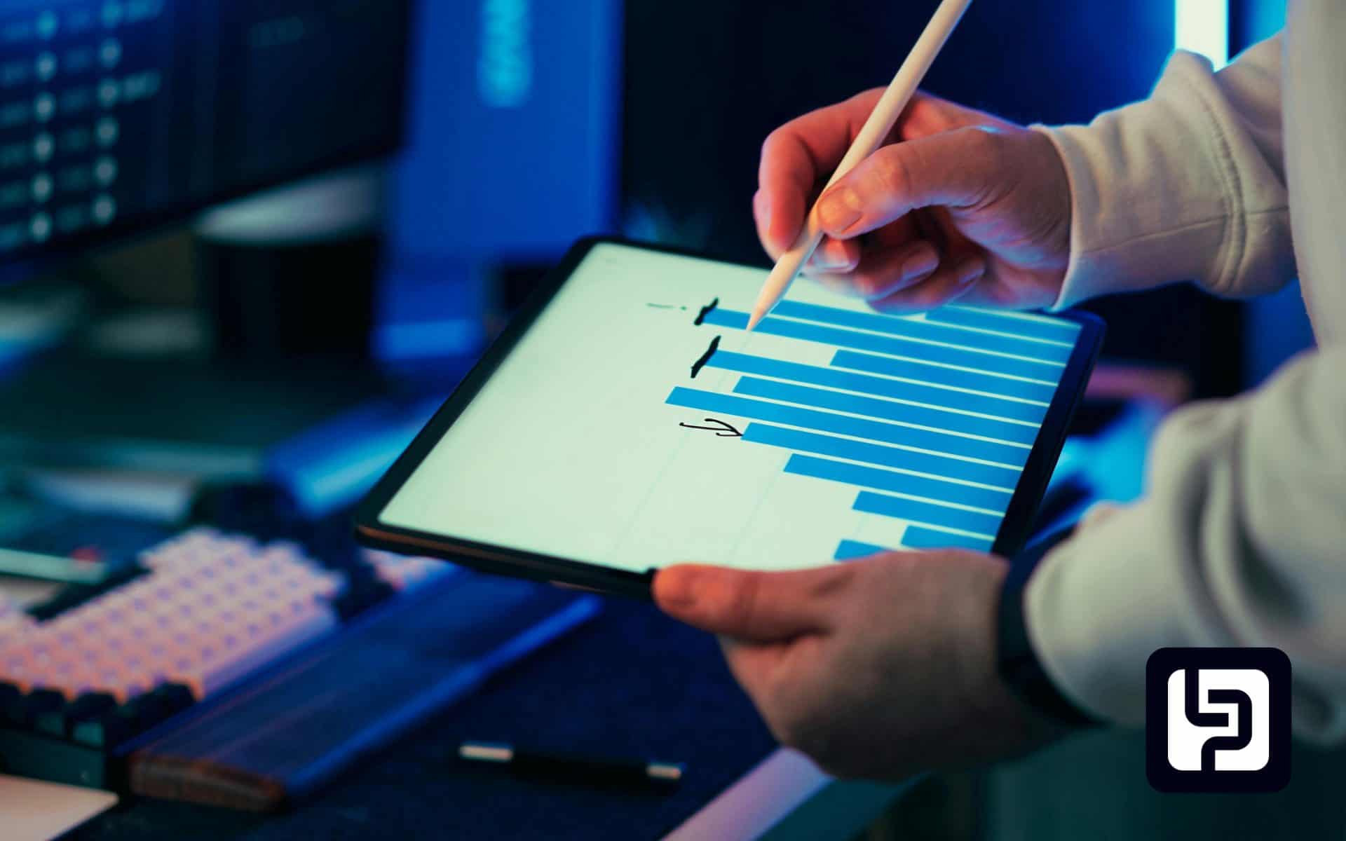 Hands with a stylus on a tablet showing a bar chart