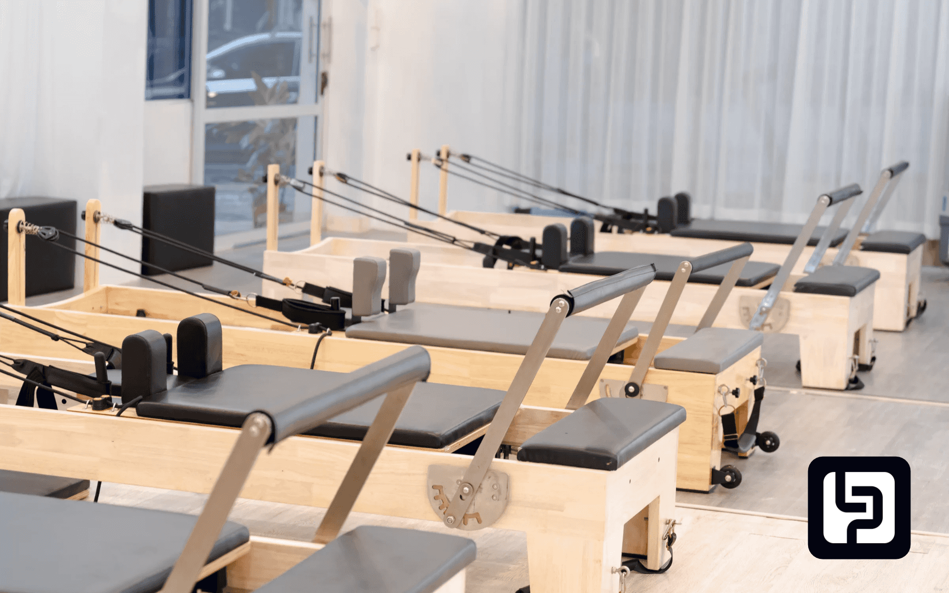 Empty bright Pilates studio with rows of wooden reformers